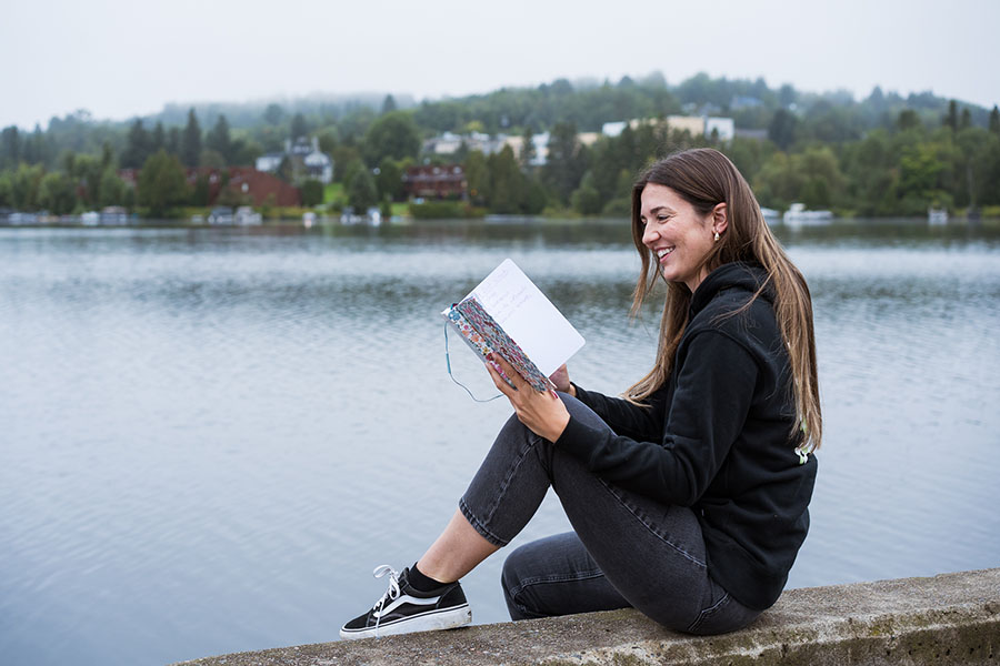 femme qui lit son carnet de notes au bord d'un lac pour ses portraits corporatifs lifestyle à Montréal